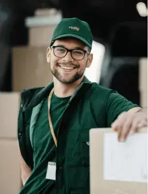 smiling ridly employee in front of loaded truck.